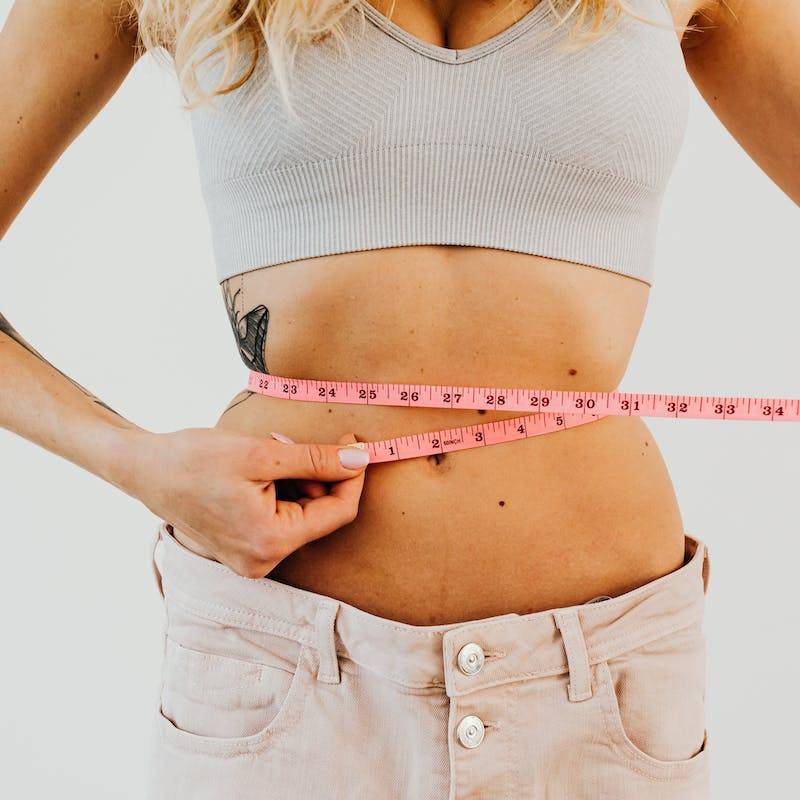 Woman in Loose Denim Measuring Her Waistline